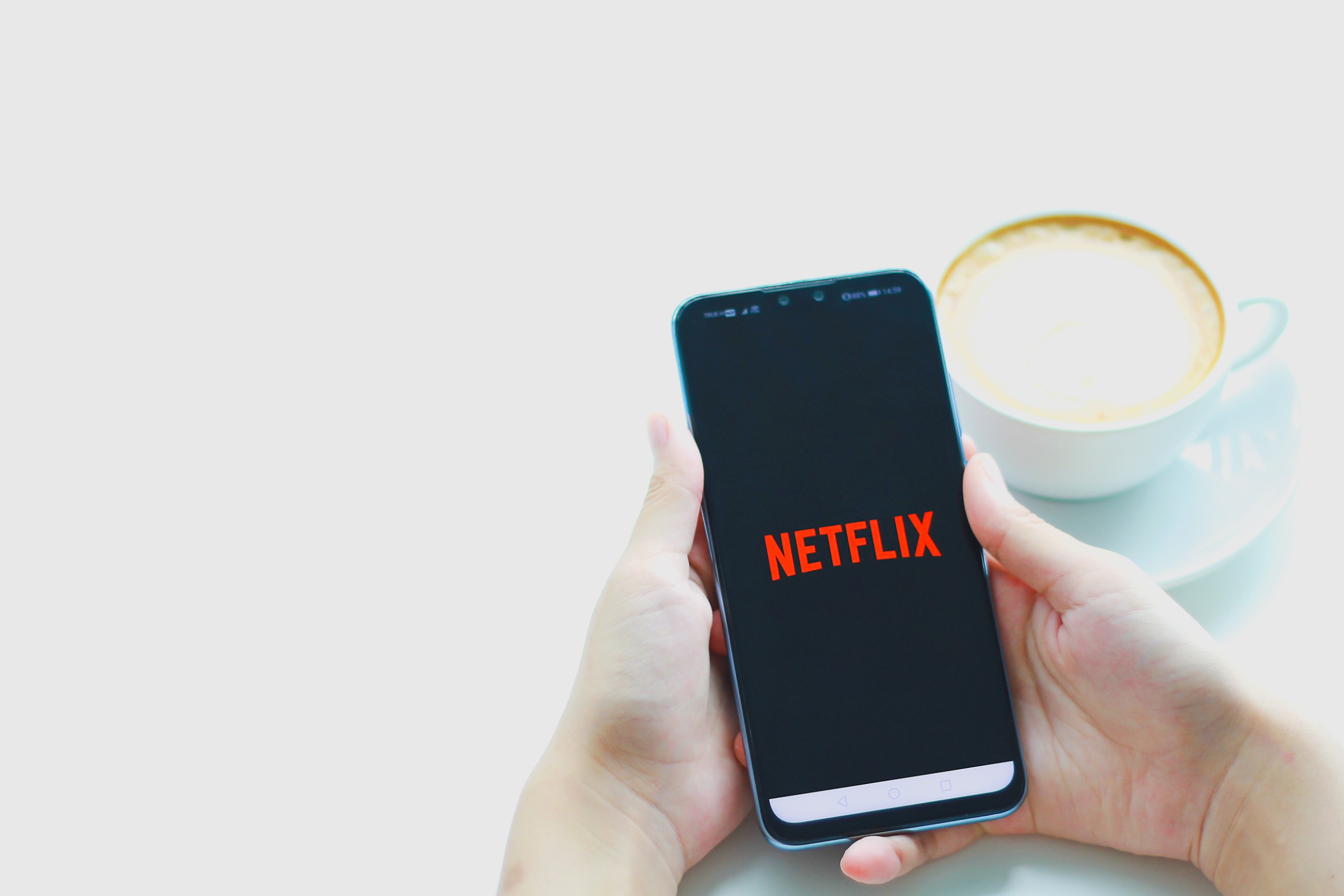 Osoba trzyma telefon Huawei, na którym wyświetla się logo Netflixa