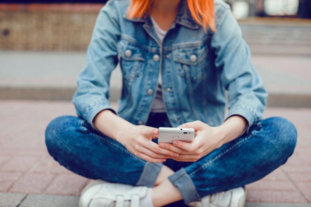 Dziewczyna korzysta ze smartfona, ubrana w modny jeansowy zestaw
